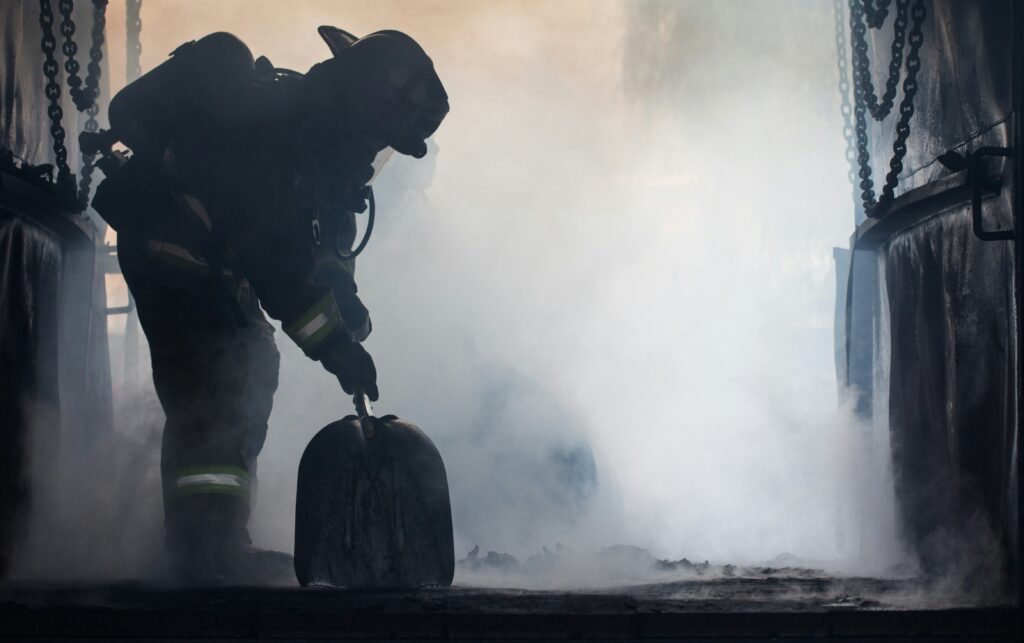 greyscale outline of firefighter lifting debris from fire-damaged building