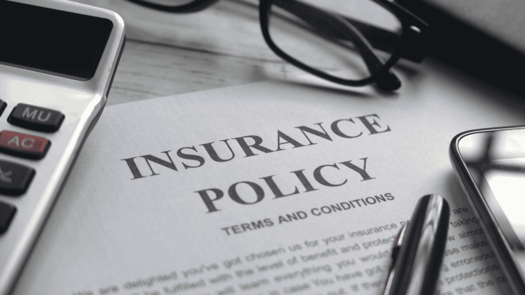 A collection of office items surrounds a paper titled Insurance Policy.