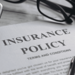 A collection of office items surrounds a paper titled Insurance Policy.