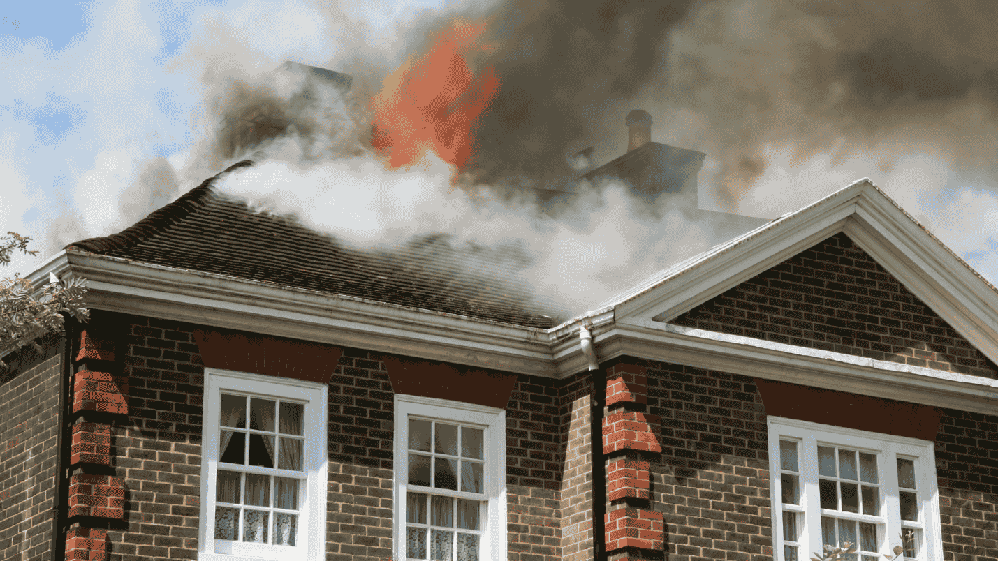 A home with smoke and fire coming from the roof.