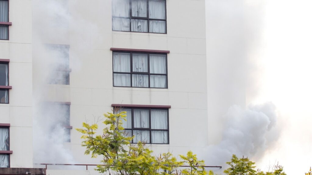 A residential building surrounded by smoke from a fire.