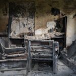 A home destroyed by fire, covered in smoke and soot damage.